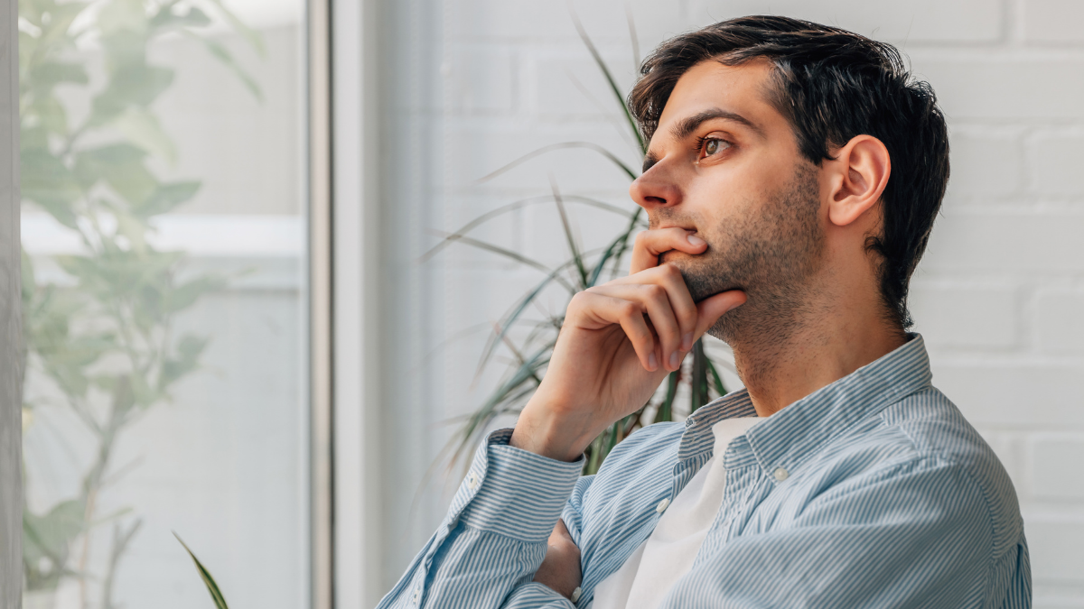 man in a blue shirt looking up pondering something.